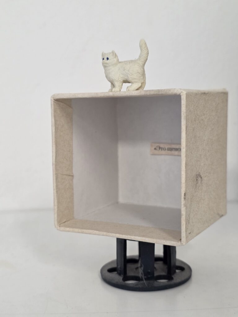A small cat figurine on a small box. An object in the exhibition 'It's OK' by Alina Glazoun. A small cat figurine on a small box. An object in the exhibition 'It's OK' by Alina Glazoun.