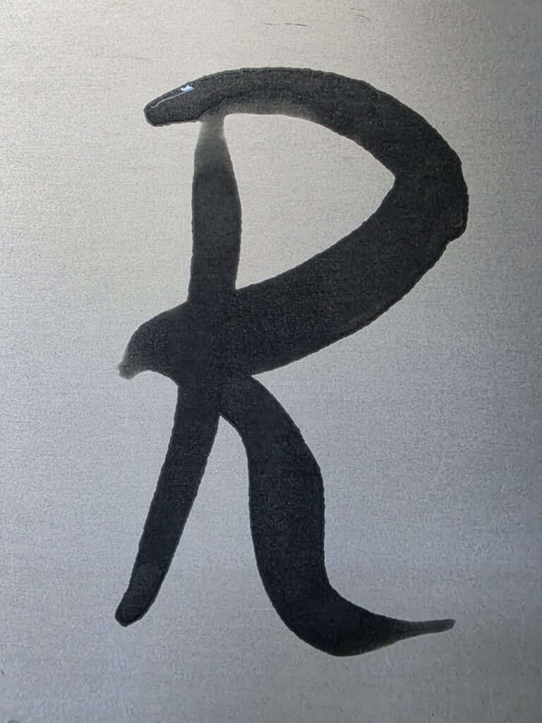'R'- wasserschrift-buchstabe auf dem buddha board für den diy-font-satz 'Habzen-Regular.ttf'.