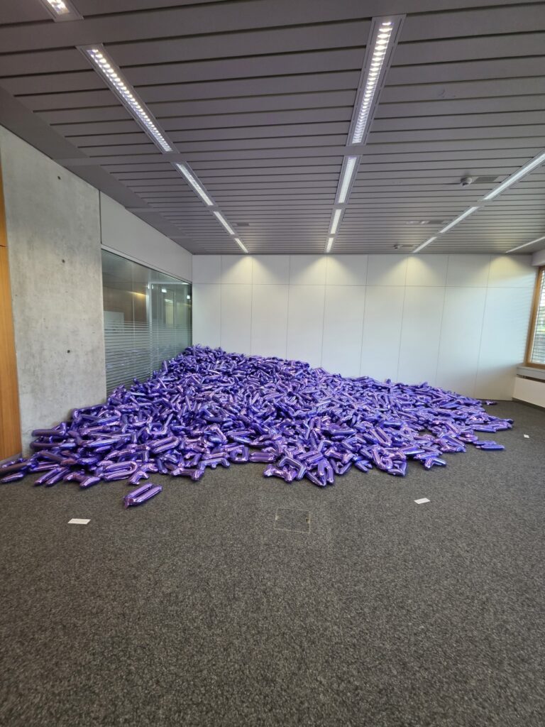 a pile of inflated letters (purple) in a corner of the Basel Social Club.
